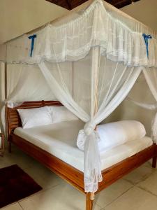 ein Schlafzimmer mit Himmelbett und weißen Vorhängen in der Unterkunft Kategha Beach Guesthouse in Praia do Tofo
