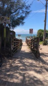 a wooden bridge leading to a beach with the ocean at Casinha com área externa in Florianópolis