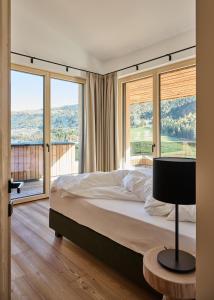 ein Schlafzimmer mit Bett und großen Fenstern in der Unterkunft Lärchenlodge SkySpa and Rooftop Pool inklusive Stubai SuperCard in Fulpmes