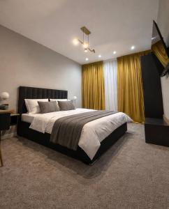 a large bedroom with a large bed and yellow curtains at Elmax Aparthotel in Craiova