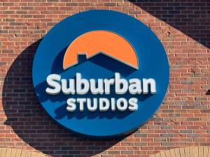 une enseigne sur un mur de briques avec une enseigne de studios de banlieue dans l'établissement Suburban Studios Charlotte - Executive Park, à Charlotte