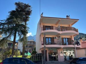 un bâtiment rose avec une voiture garée devant lui dans l'établissement Kalavryta Moments, à Kalavrita