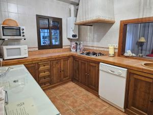 una cucina con armadi in legno e un piano cottura bianco con forno di La Casa de Monica ad Aracena Altre 32 foto