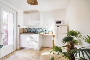 Gîtes Mas des rochers - Case bambou avec Spa في لو بوزيت: مطبخ بخزائن بيضاء وثلاجة بيضاء