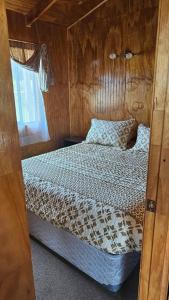 a bedroom with a bed with a wooden wall at Cabañas El Maiten de Castro in La Chacra