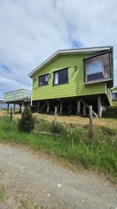 a green house is sitting on the side of a road at Cabañas El Maiten de Castro in La Chacra
