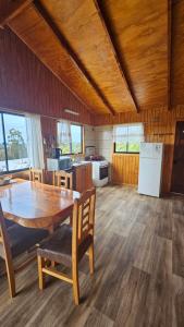 a kitchen and dining room with a wooden table and chairs at Cabañas El Maiten de Castro in La Chacra