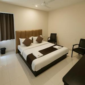 a bedroom with a large bed and two chairs at Hotel Rukmani Palace in Ujjain