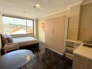 a room with a bed and a kitchen with a window at Suitesecu Rentals Cuenca in Cuenca +32 photos