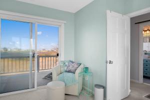 ein Wohnzimmer mit einem Stuhl und einem Balkon in der Unterkunft Island SunRise in Plum Island + 42 Fotos