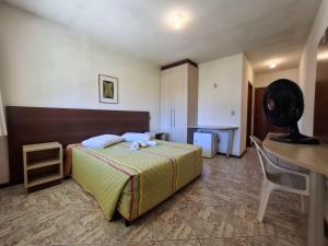 ein Schlafzimmer mit einem Bett, einem Schreibtisch und einem Stuhl in der Unterkunft Marina Sul Hotel in Laguna