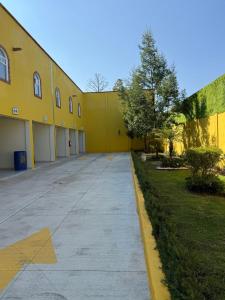 a yellow building with a sidewalk in front of it at Hotel-Motel Calens in Velasco