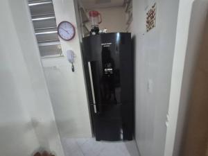 een zwarte koelkast in een kamer met een klok aan de muur bij SUH Copacabana 143 in Rio de Janeiro