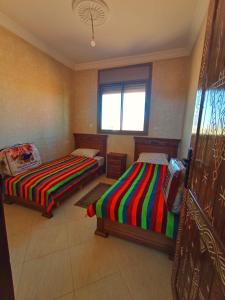 una habitación con dos camas y una ventana en Wave Riders Hostel, en Mirleft