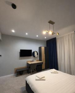 a bedroom with a bed and a desk and a television at Elmax Aparthotel in Craiova
