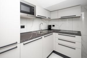 een witte keuken met een spoelbak en een magnetron bij Prince Residence in Castellammare di Stabia
