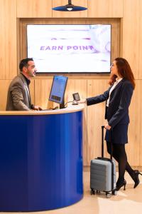 een vrouw die handen schudt met een man aan een bureau bij Mercure Bucharest Cantemir in Boekarest