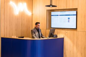un homme debout sur un bureau avec un ordinateur portable dans l'établissement Mercure Bucharest Cantemir, à Bucarest