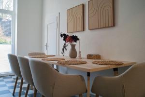 a dining room table with chairs and a vase with flowers at MS-Apartments I Quartier 4 in Leer