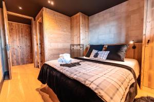 een slaapkamer met een bed met een houten muur bij Chalet « Le 1712 » direct pistes in Les Angles +21 foto's