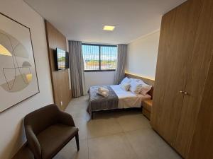 a bedroom with a bed and a chair and a window at Estúdios Completos no Centro de Floripa - CMA in Florianópolis