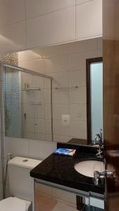 un bagno con lavandino, WC e specchio di Casa Buritis a Primavera do Leste