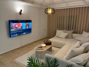 een woonkamer met een bank en een tv aan de muur bij Tanja Pearl in Tanger