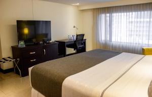 um quarto com uma cama, uma escrivaninha e uma televisão em Sonesta Hotel Cali em Cali