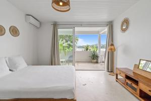 a bedroom with a white bed and a sliding glass door at Casa Blanca in La Trinité