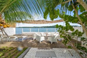a patio with white chairs and a table and the ocean at Casa Blanca in La Trinité
