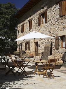 uma mesa e cadeiras com um guarda-sol em frente a um edifício em Posada Molino del Canto em Barriolacuesta