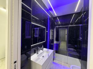 a bathroom with a white sink and blue lighting at D'ANNUNZIO suites in Martinsicuro +55 photos