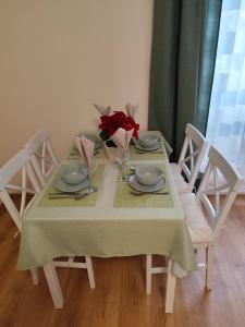 a table with a green table cloth and roses on it at Tímea Apartman Pécs in Pécs