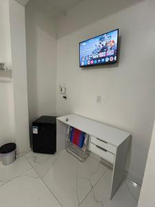 a desk in a room with a tv on the wall at HOTEL e POUSADA KF in Irapuá