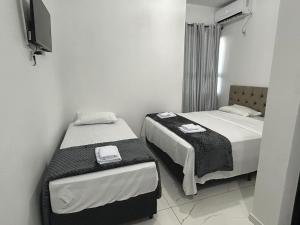 a bedroom with two beds and a tv on the wall at HOTEL e POUSADA KF in Irapuá