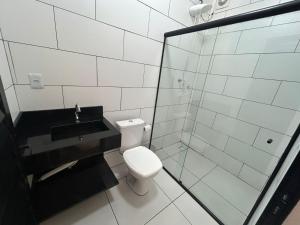 a bathroom with a toilet and a sink and a shower at HOTEL e POUSADA KF in Irapuá