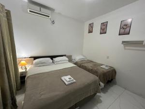a bedroom with two beds and a night stand with a lamp at HOTEL e POUSADA KF in Irapuá