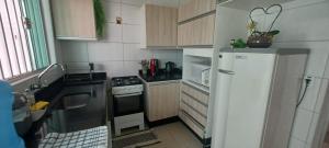 a small kitchen with a refrigerator and a stove at Casa confortável com garagem coberta in Primavera do Leste