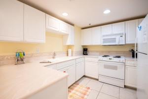 a white kitchen with white cabinets and a microwave at The Terraces #202-Condo - Pool in Fernandina Beach