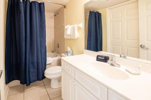 a bathroom with a toilet and a blue shower curtain at The Terraces #202-Condo - Pool in Fernandina Beach
