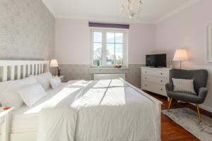 a bedroom with a white bed and a chair and a television at Hotel Villa Wahnfried Thiessow in Thiessow