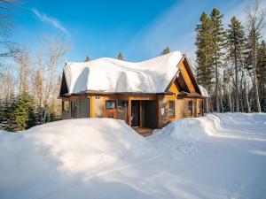 een huis bedekt met sneeuw met een berg sneeuw bij The Bear - Escapade en Nature avec Spa in Petite-Rivière-Saint-François