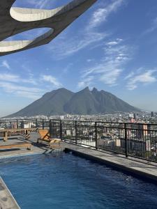 einen Pool auf einem Gebäude mit Bergen in der Unterkunft Bonito y cómodo loft en el centro de Monterrey! in Monterrey