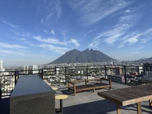 Ein Balkon mit Bänken und einem Berg im Hintergrund in der Unterkunft Bonito y cómodo loft en el centro de Monterrey! in Monterrey