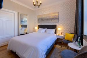 een slaapkamer met een groot wit bed en een stoel bij Hotel Villa Wahnfried Thiessow in Thiessow