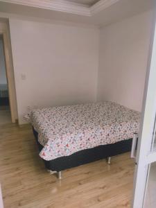 een slaapkamer met een bed in een kamer met houten vloeren bij Apartamento 150m das Termas in Piratuba