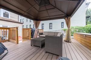 een patio met een bank en een parasol op een terras bij Massive NYC House with Pool Table in Yonkers