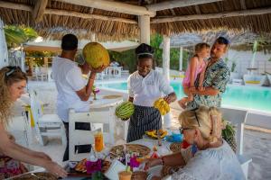 a group of people standing around a table with food at ZAN Uhuru Beach in Jambiani