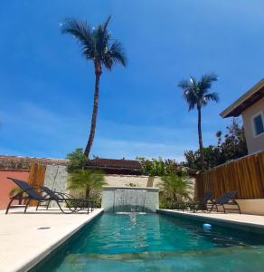 uma piscina com cadeiras e palmeiras em Pousada Pantai Maresias em Maresias