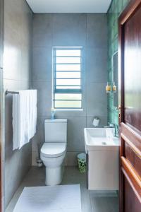 a bathroom with a toilet and a sink and a window at charming retreat in Gaborone +11 photos